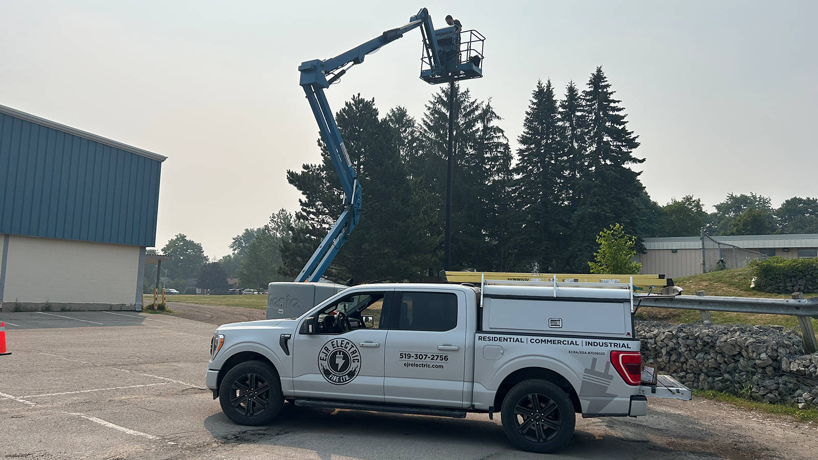 EJR Electric service truck parked outside a commercial property with an electrician working on a boom lift.